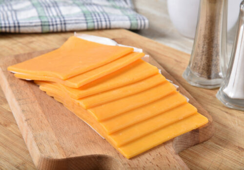 Thick slices of cheddar cheese on a wooden cutting board